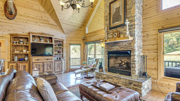 Un interior de cabaña acogedor con chimenea de piedra, muebles de cuero y estanterías de madera.