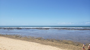 Ein Strand mit felsiger Küste und blauem Himmel.