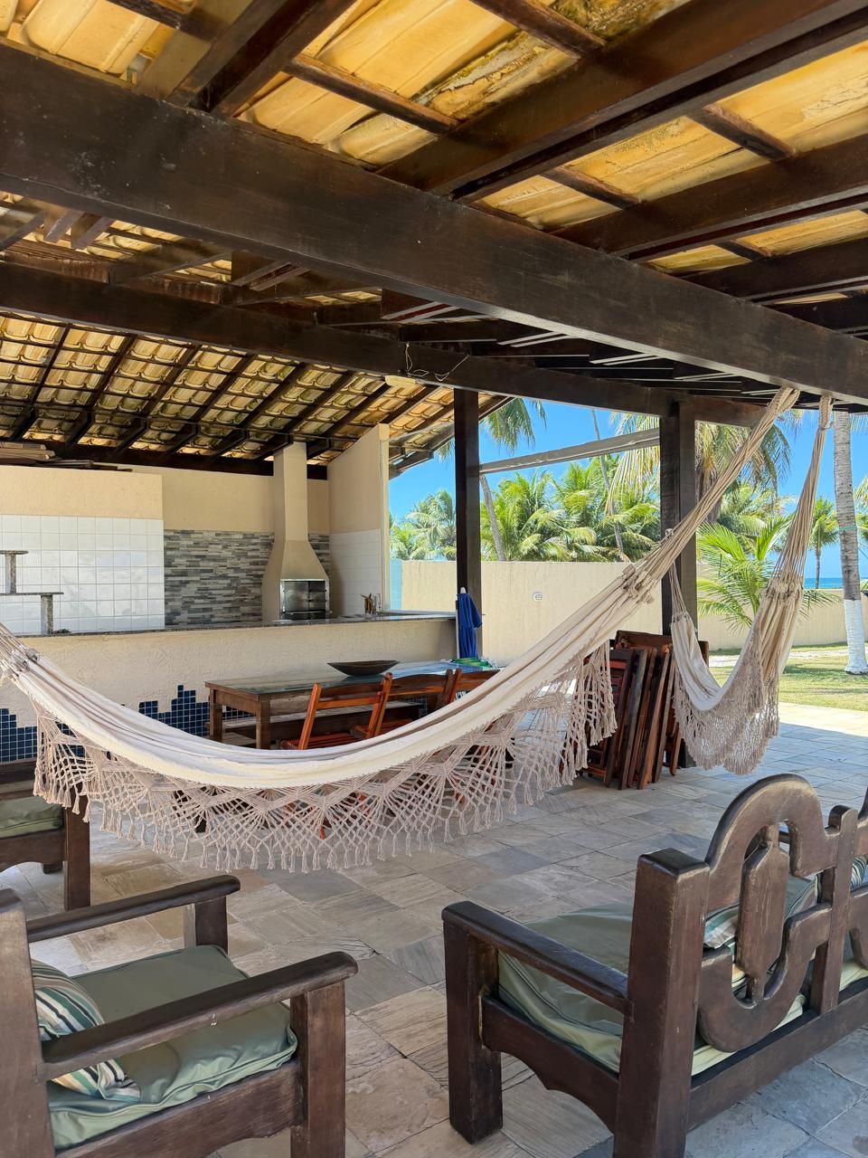 A covered outdoor seating area with a hammock, a table, and chairs.