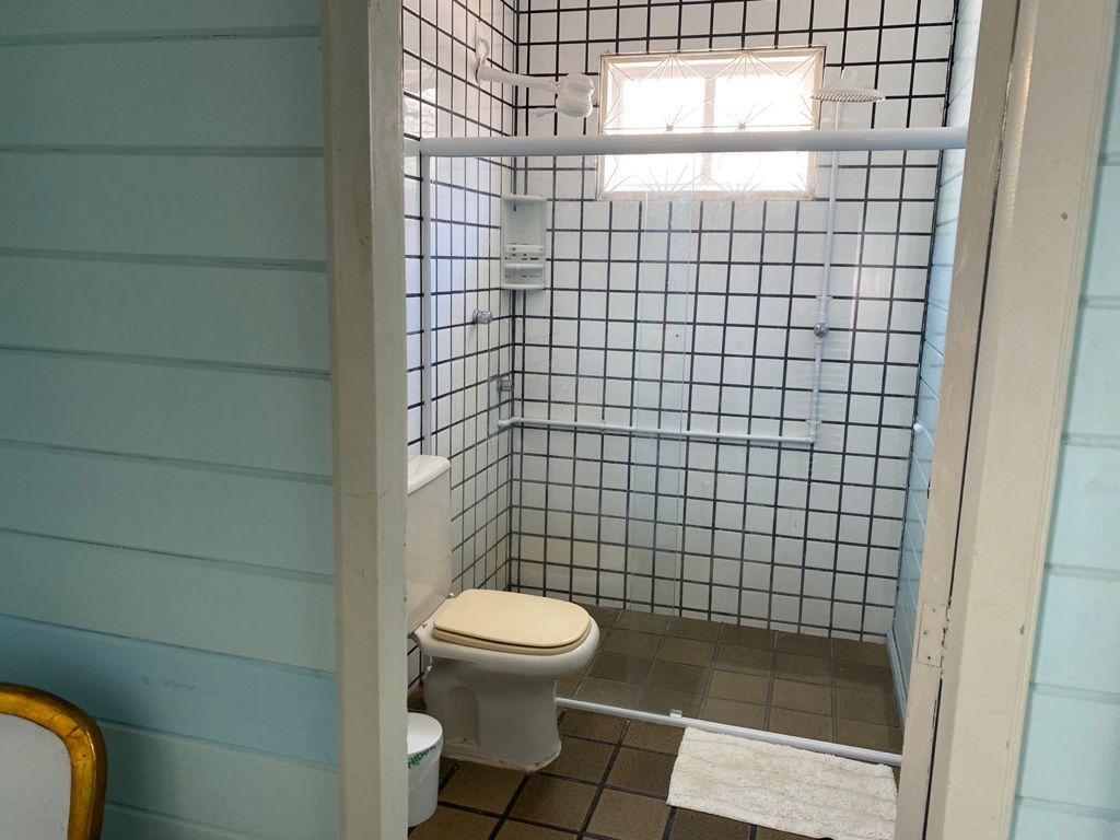 Een kleine badkamer met toilet, douche en raam.