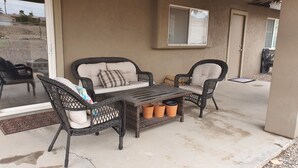 A patio with wicker furniture, including a sofa and chairs, and a small table with terracotta pots.