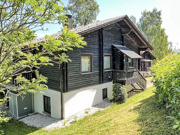 A two-story log cabin with a balcony and a small attached shed.