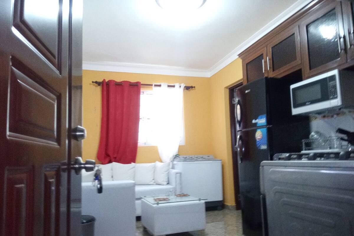 Una cocina compacta equipada con refrigerador, microondas y un comedor con una mesa y sillas blancas.