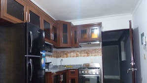 Una cocina con armarios de madera, un refrigerador negro, una estufa y un lavabo.