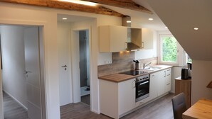 Una cocina moderna con vigas de madera, armarios blancos y un ventanal grande.