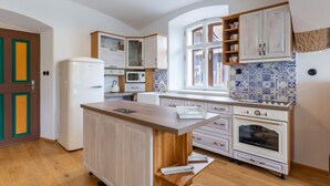 A compact kitchen with a central island, white cabinetry, a microwave, a stove, and a window with a view. - Dolní Olešnice by Interhome (Hostinne)