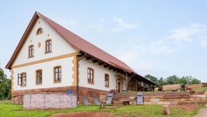 A traditional two-story building with a sloped roof, a brick foundation, and a covered porch area. - Dolní Olešnice by Interhome (Hostinne)