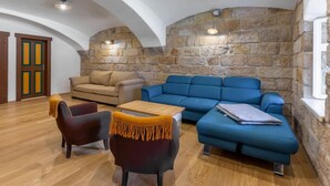 A cozy living room with a stone wall, a beige sofa, a blue sofa, and a wooden table. - Dolní Olešnice by Interhome (Hostinne)
