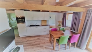 Une cuisine de taille réduite avec des meubles blancs, une table à manger en bois et des chaises colorées.