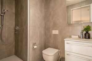 A modern bathroom with a shower, toilet, and vanity.