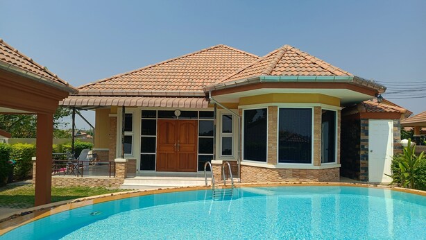Ein Wohnhaus mit Schwimmbad, einer überdachten Terrasse und einer großen Holztür.