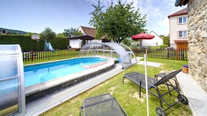 A swimming pool with a glass enclosure, a slide, and a fenced yard with a house and a tree. - Neurazy by Interhome (Neurazy)