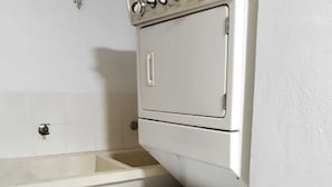 A compact kitchen with a built-in washing machine and a sink. - Residencial Las Dianas (Santiago de los Caballeros)