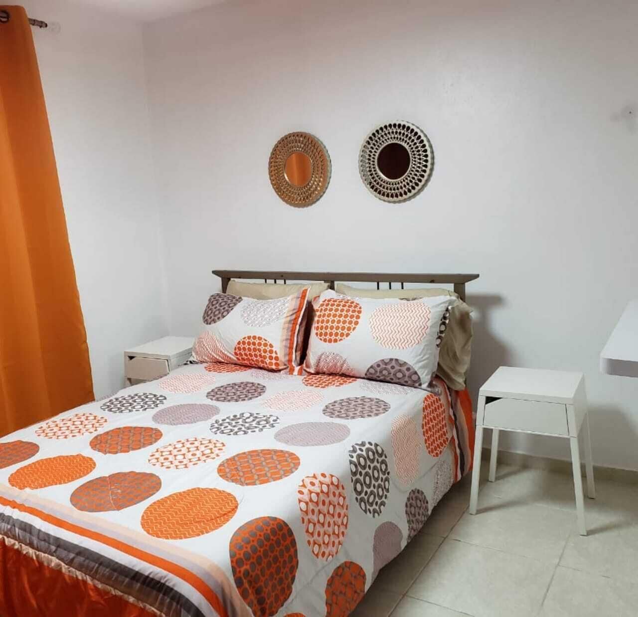 A bedroom with a bed, two bedside tables, and a nightstand.