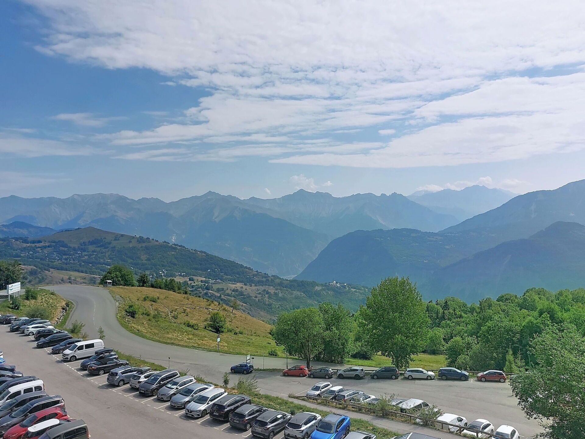 Un parking rempli de voitures, avec une chaîne de montagnes en arrière-plan.