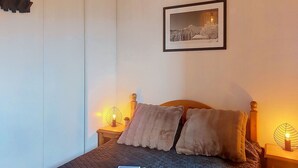 A bedroom with a bed, two bedside lamps, a framed picture on the wall, and a bedside table with a plant. - Nice apartment for 6 guests with WIFI, pool, TV and balcony (Le Corbier)