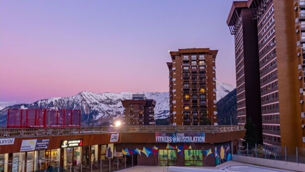 A swimming pool with a view of a mountain range and a building with a fitness center sign. - Nice apartment for 6 guests with WIFI, pool, TV and balcony (Le Corbier)