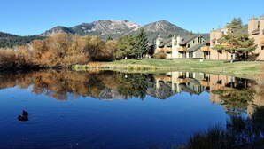 Vista del lago con montañas al fondo, reflejando edificios y árboles.
