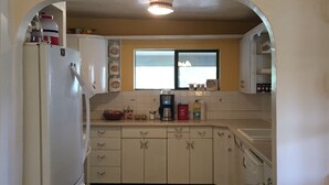 A compact kitchen with white cabinets, a refrigerator, and a window providing natural light. - Hunters, Hikers, Campers Welcome! (Mule Creek)