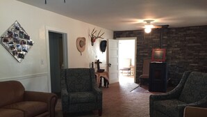 A living room with patterned armchairs, a brown sofa, a fireplace, and wall-mounted deer antlers. - Hunters, Hikers, Campers Welcome! (Mule Creek)