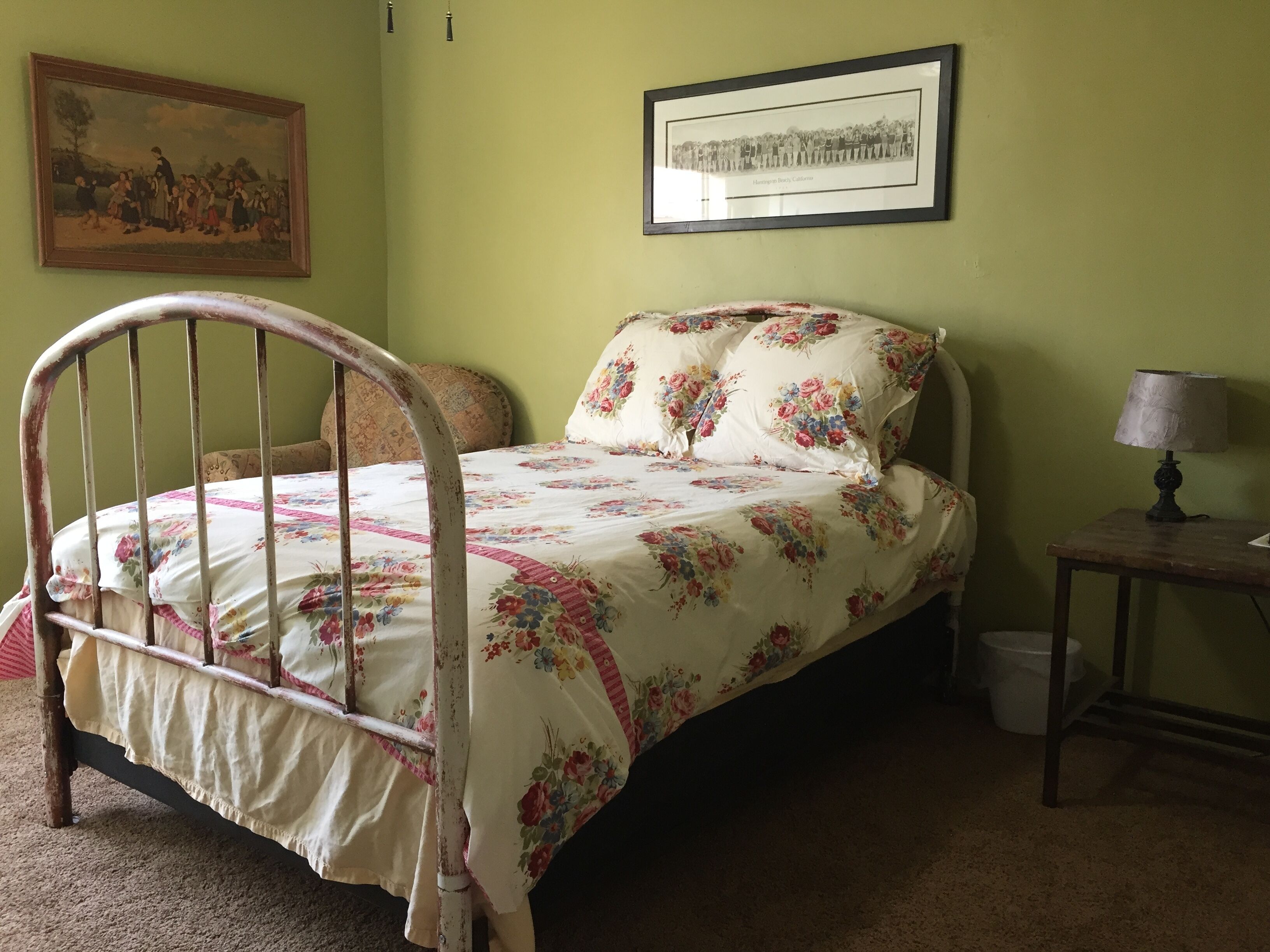 Un dormitorio con una cama, un cuadro en la pared y una mesita de noche con una lámpara.