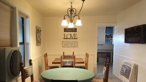 A dining area with a round table and chairs, a chandelier, and a wall with 'Smile LOVE HOPE' signs. - Hunters, Hikers, Campers Welcome! (Mule Creek)