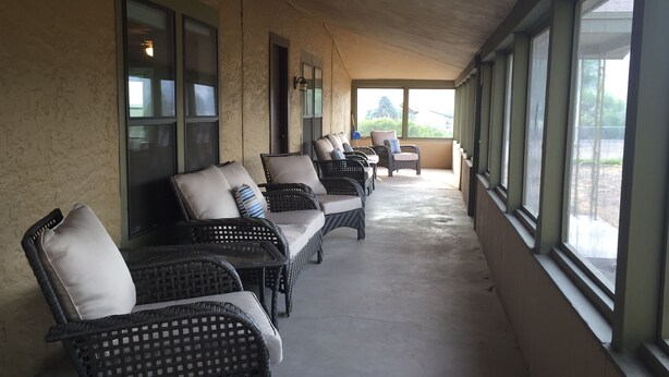 A covered outdoor seating area with wicker furniture and large windows. - Hunters, Hikers, Campers Welcome! (Mule Creek)