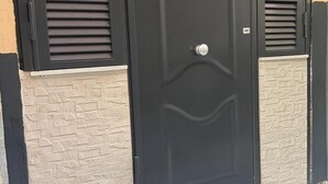 A black door with a silver handle, flanked by two black shutters with horizontal slats. - Graphite House 2.0 (Napoli)