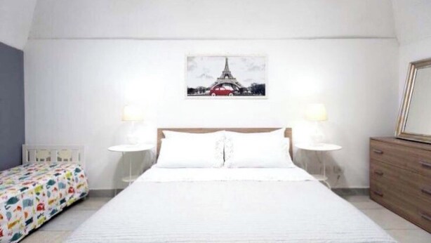 A bedroom with a bed, two bedside lamps, a dresser, and a picture of the Eiffel Tower on the wall. - Graphite House 2.0 (Napoli)