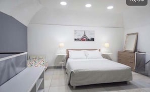 A bedroom with a bed, bedside tables, a bench, a dresser, and a picture of the Eiffel Tower. - Graphite House 2.0 (Napoli)