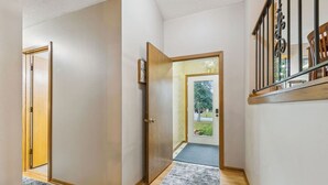 A hallway with a wooden door, a mat, and a staircase with a railing.