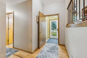 A hallway with a wooden door, a mat, and a staircase with a railing.
