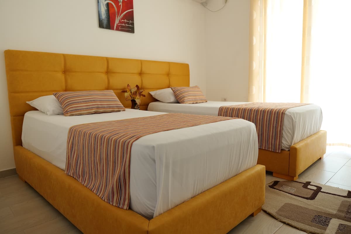 Een hotelkamer met twee bedden, elk voorzien van een gestreepte deken en hoofdbord.