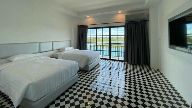 A hotel room with two beds, a checkered floor, a large window with a view, and a flat-screen TV.