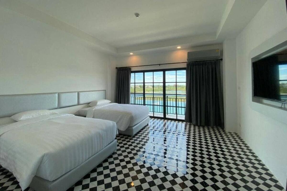 A hotel room with two beds, a checkered floor, a large window with a view, and a flat-screen TV.