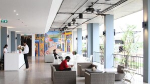 A spacious lobby with a reception desk, seating area, and a mural on the wall.