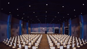A large conference room with rows of chairs facing a stage.