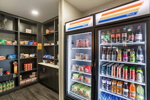 Máquina automática com diversas bebidas e petiscos, e um refrigerador com alimentos embalados.