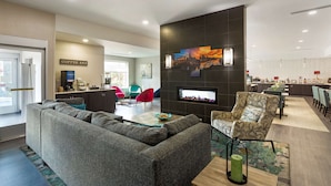 Un espace de vie moderne comprenant un canapé, des fauteuils, un coin bar et une cheminée.