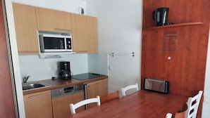 A compact kitchen with a microwave, coffee maker, toaster, and a sink. There is a wooden dining table with chairs. - Pleasant duplex with parking - 7 guests (La Mongie)