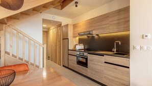 A modern kitchen with wooden cabinets, a built-in oven, and a stainless steel sink. - Cozy duplex with pool and spa, ski-in/ski-out (Les Arcs 1600)