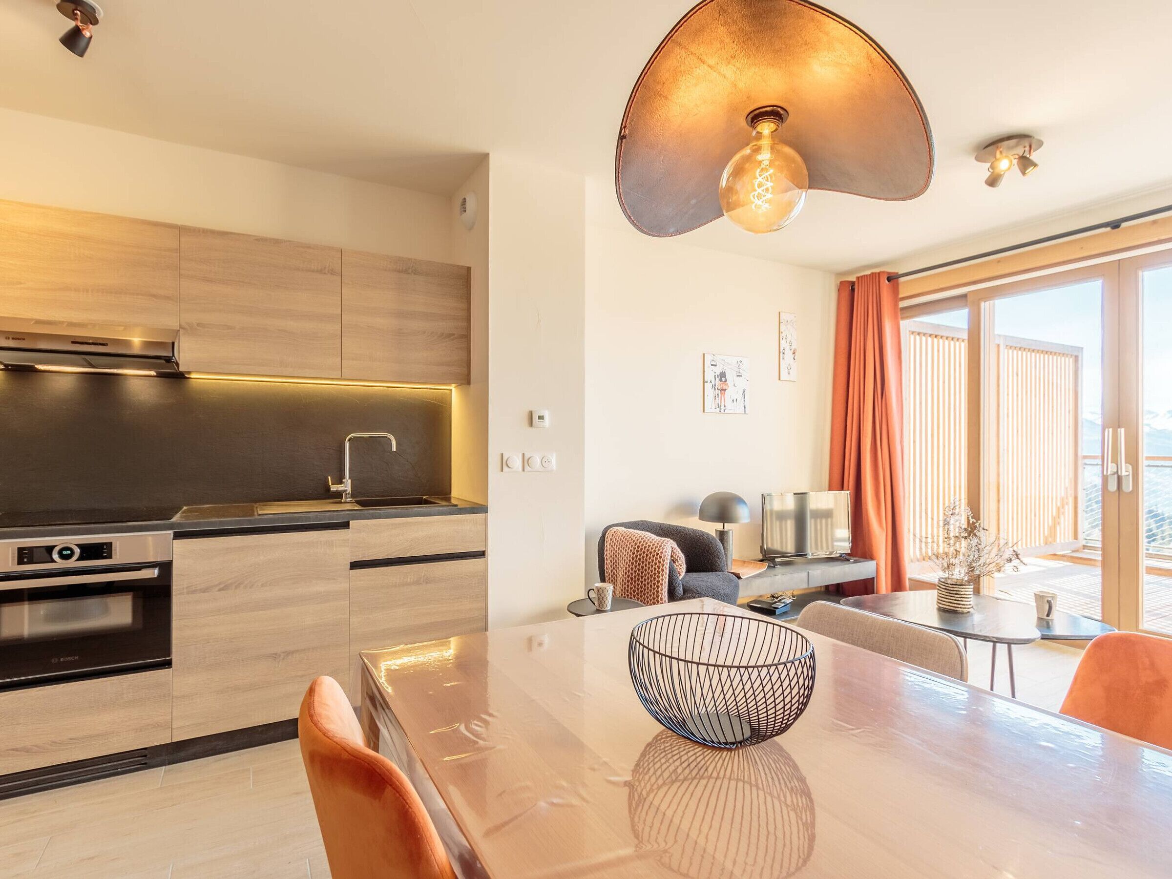 Una cocina moderna con comedor, que incluye una mesa grande, sillas y una lámpara original.