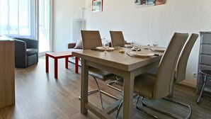 Un espace repas moderne avec un plafond en bois, une grande fenêtre et un tableau au mur.