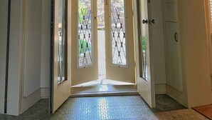 A hallway with a decorative ceiling, a door with a metal gate, and a tiled floor. - Mushroom House, Earl Young’s Personal Residence overlooking Lake MI! New AC!  (Charlevoix)