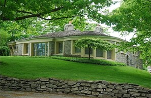 Surrounded by lush greenery, this house features a well-maintained lawn and a stone facade.