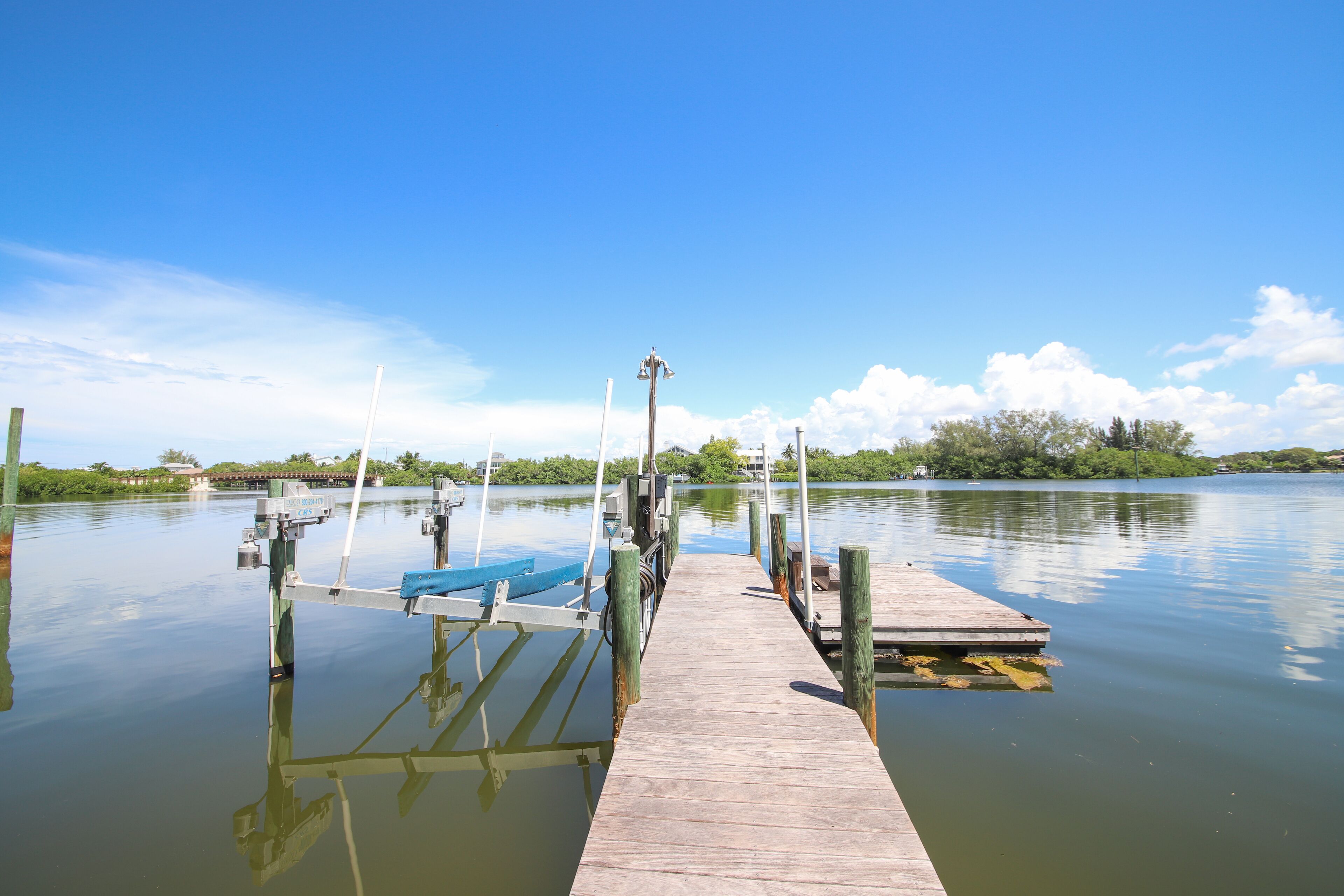 A wooden dock extending into calm water with a clear sky above.