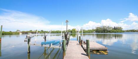 A wooden dock extending into calm water with a clear sky above.