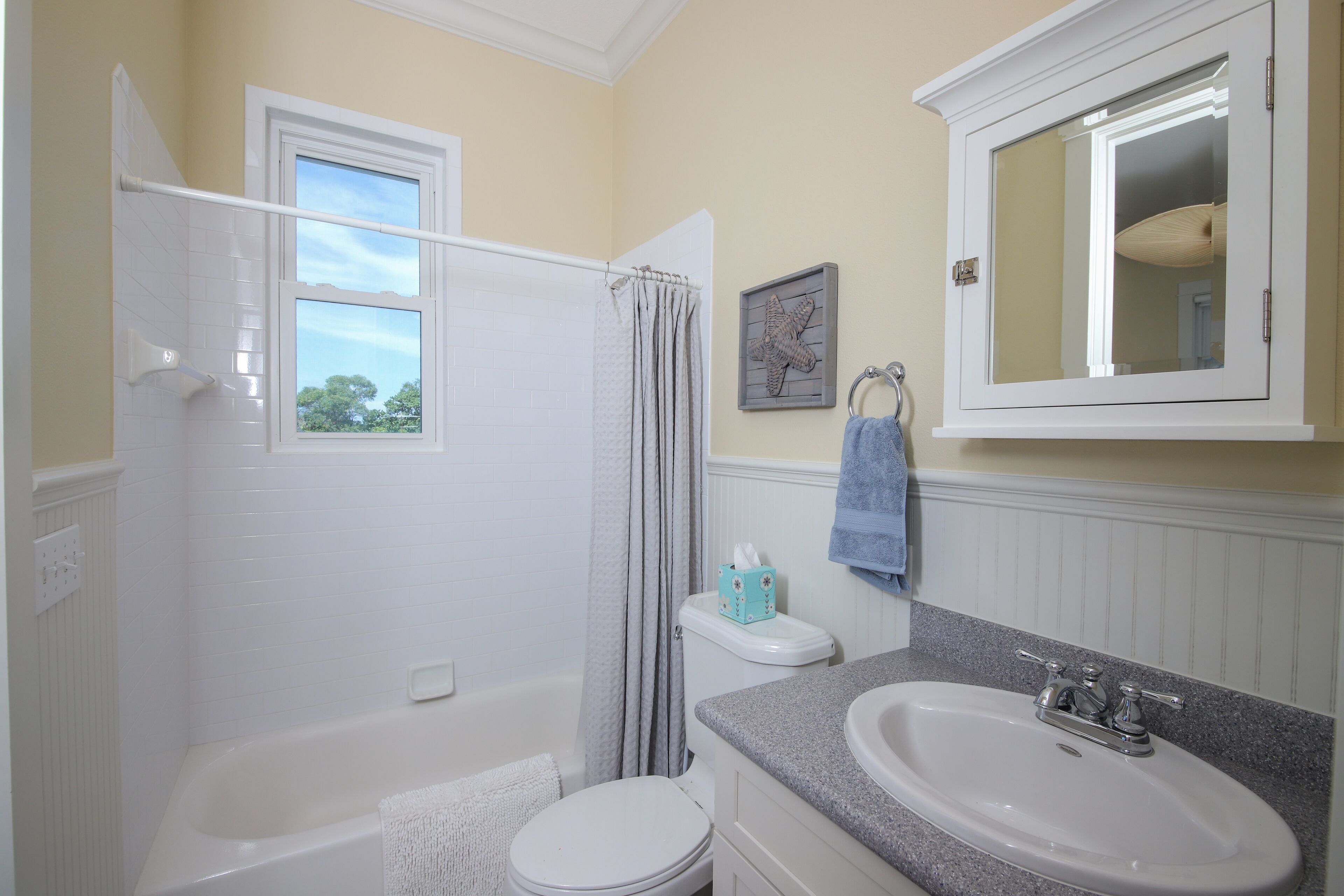 A bathroom with a bathtub, toilet, sink, and a window.