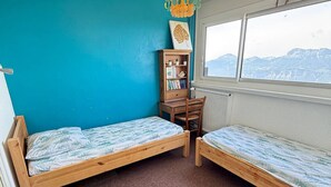 A room with two wooden beds, a desk, a bookshelf, and a window with a mountain view. - 3-room apartment at the foot of the slopes, 7th floor (Les Adrets-Prapoutel)