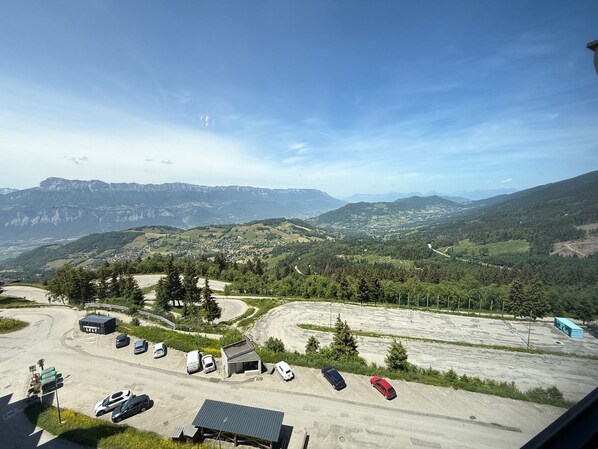 A parking area with several cars, a small building, and a view of a mountainous landscape.